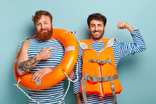 Two men, one wearing a life jacket and one carrying a life ring